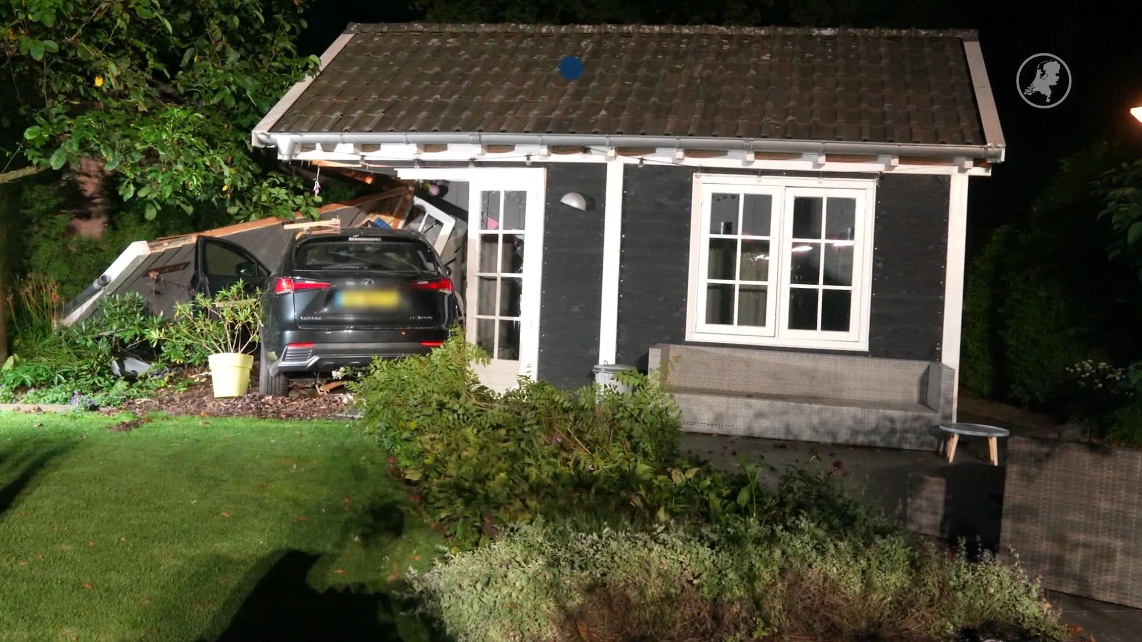 Auto ramt verkeersborden, hek en tuinhuisje in Asten