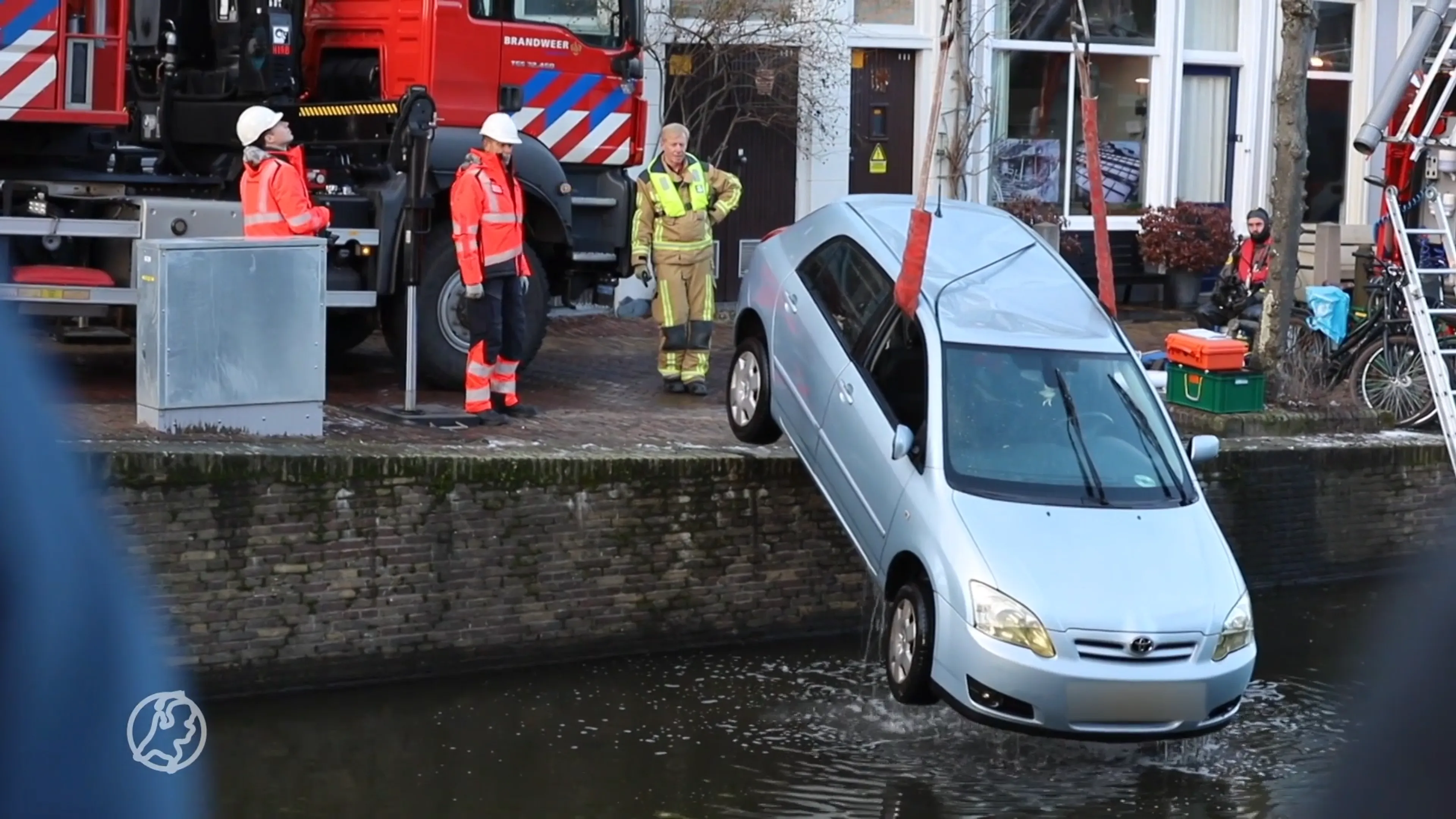 Vrouw glijdt met auto de Delftse gracht in, wagen total loss