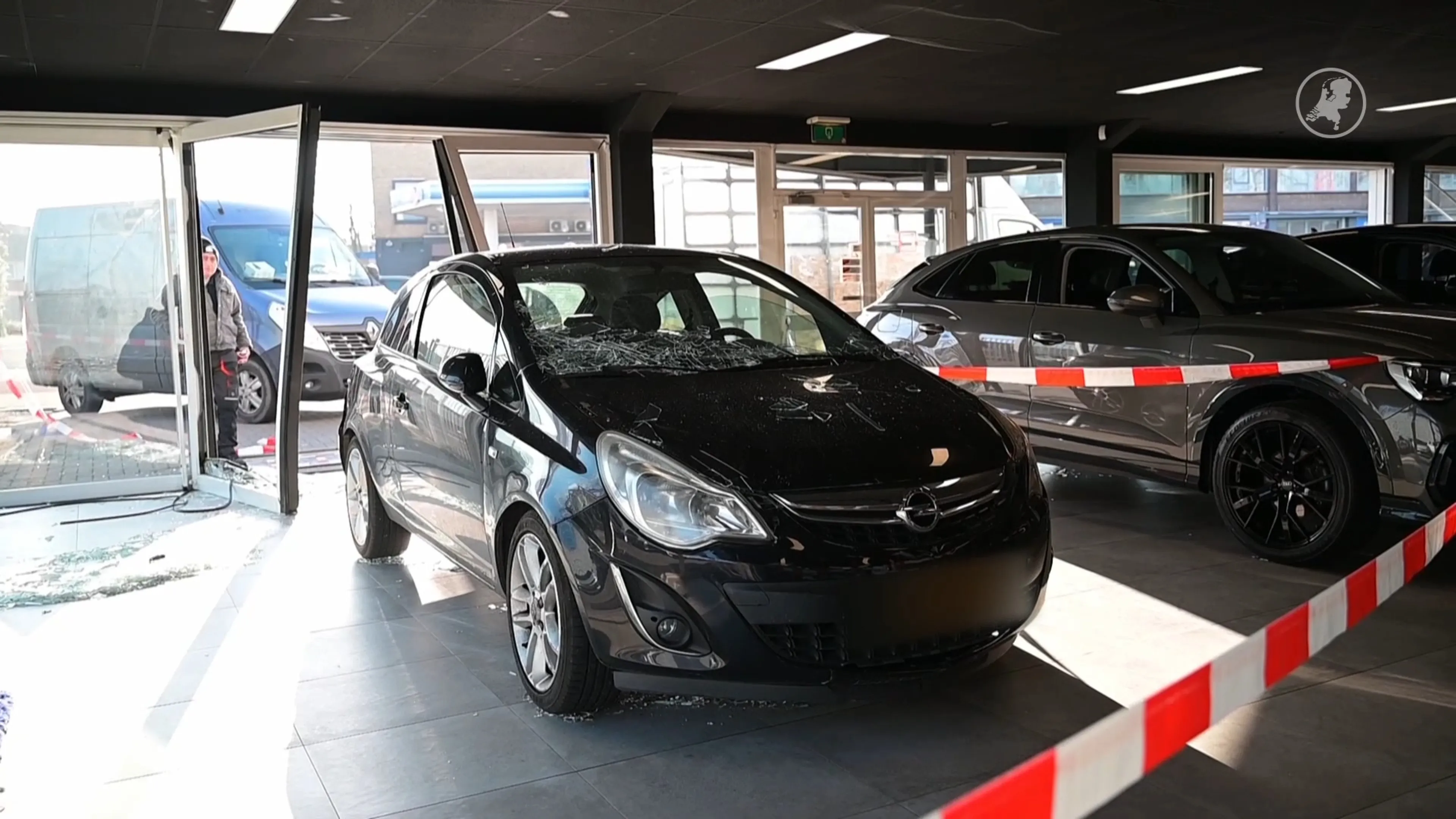 Auto botst met lijnbus en rolt dwars door gevel van showroom heen