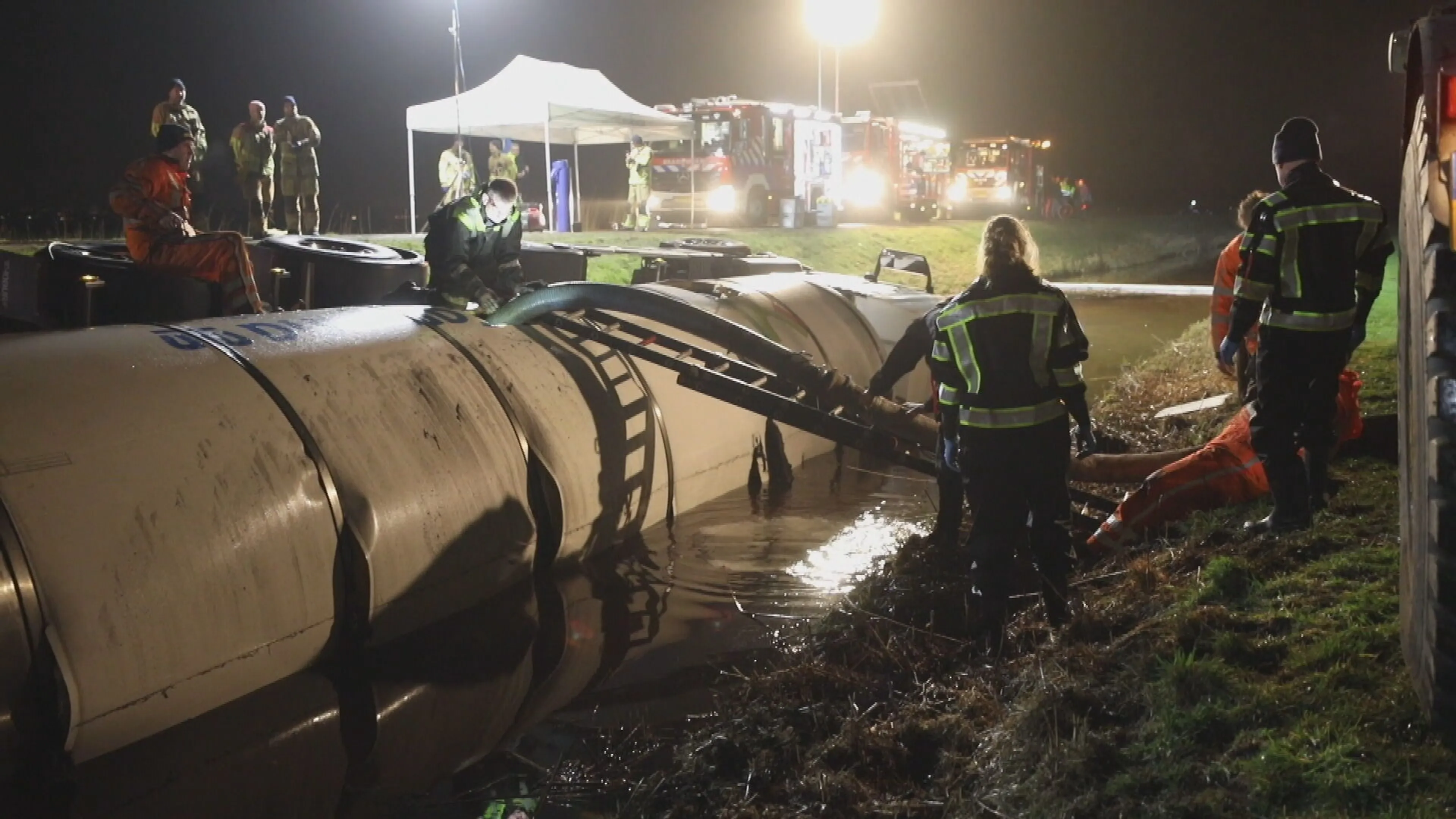 Tankwagen met duizenden liters melk glibbert van de weg en belandt in water
