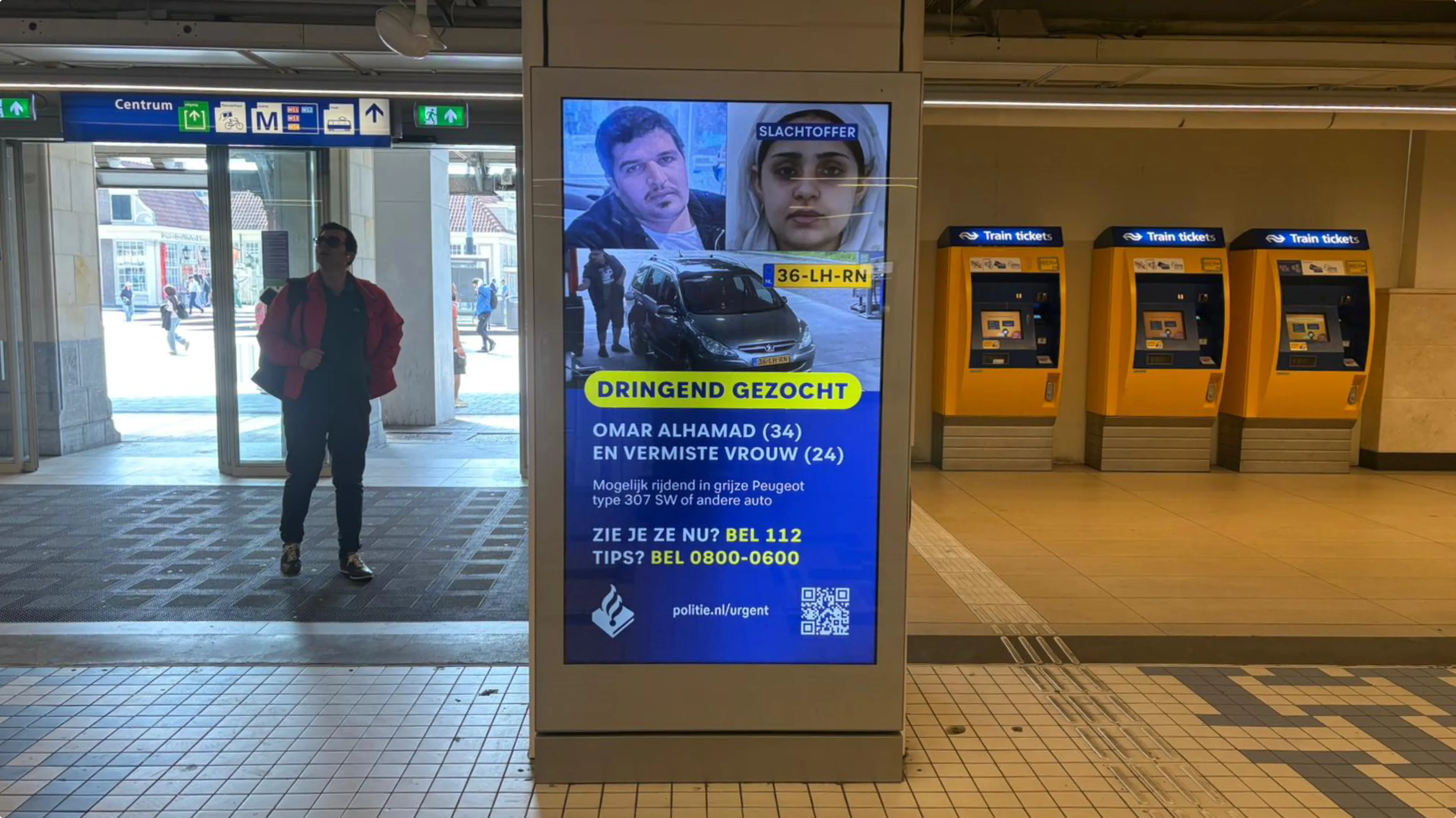 Foto's van de vrouw en de man worden vertoond op digitale borden zoals hier op Amsterdam Centraal. Beeld: Redactie