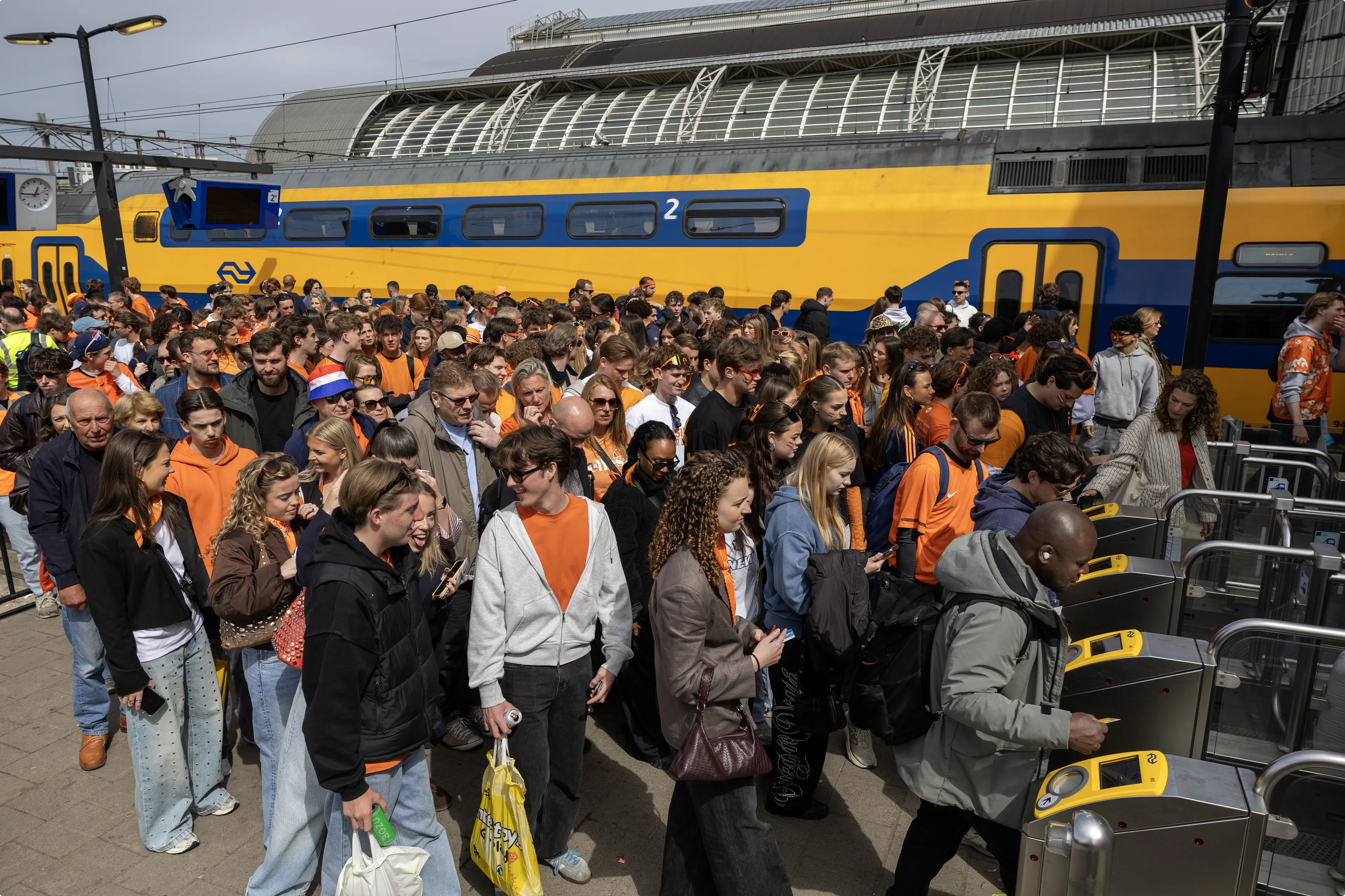 Feestvierders arriveren op station Amsterdam Centraal om in de hoofdstad Koningsdag te vieren. Beeld: ANP