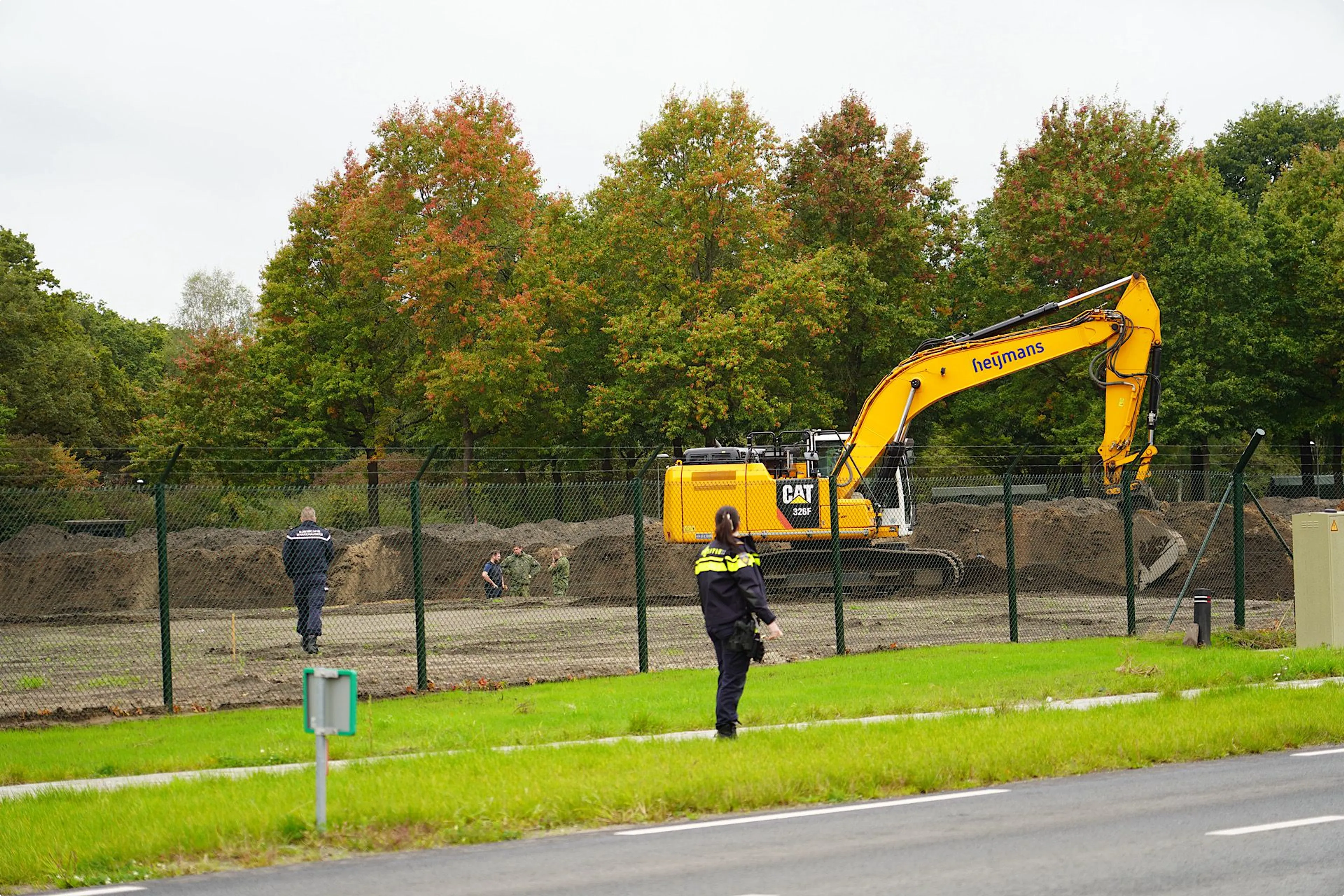 Beeld: SQ Vision. Militairen kijken naar de gevonden bom op vliegbasis Gilze-rijen.