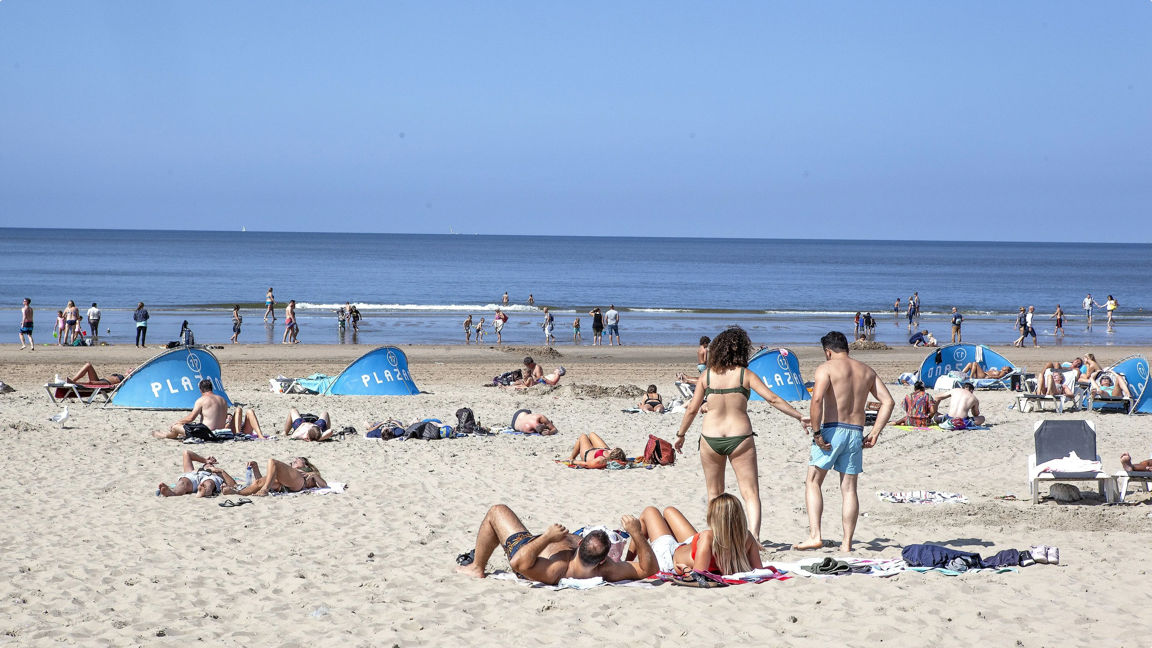 Strandgangers genieten van het zonnetje bij Zandvoort. Beeld: ANP.